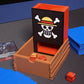 One Piece Dice Tower opened up with red and gold dice in the tray and next to it while sitting on a black playmat next to a Belo Betty deck from OPTCG