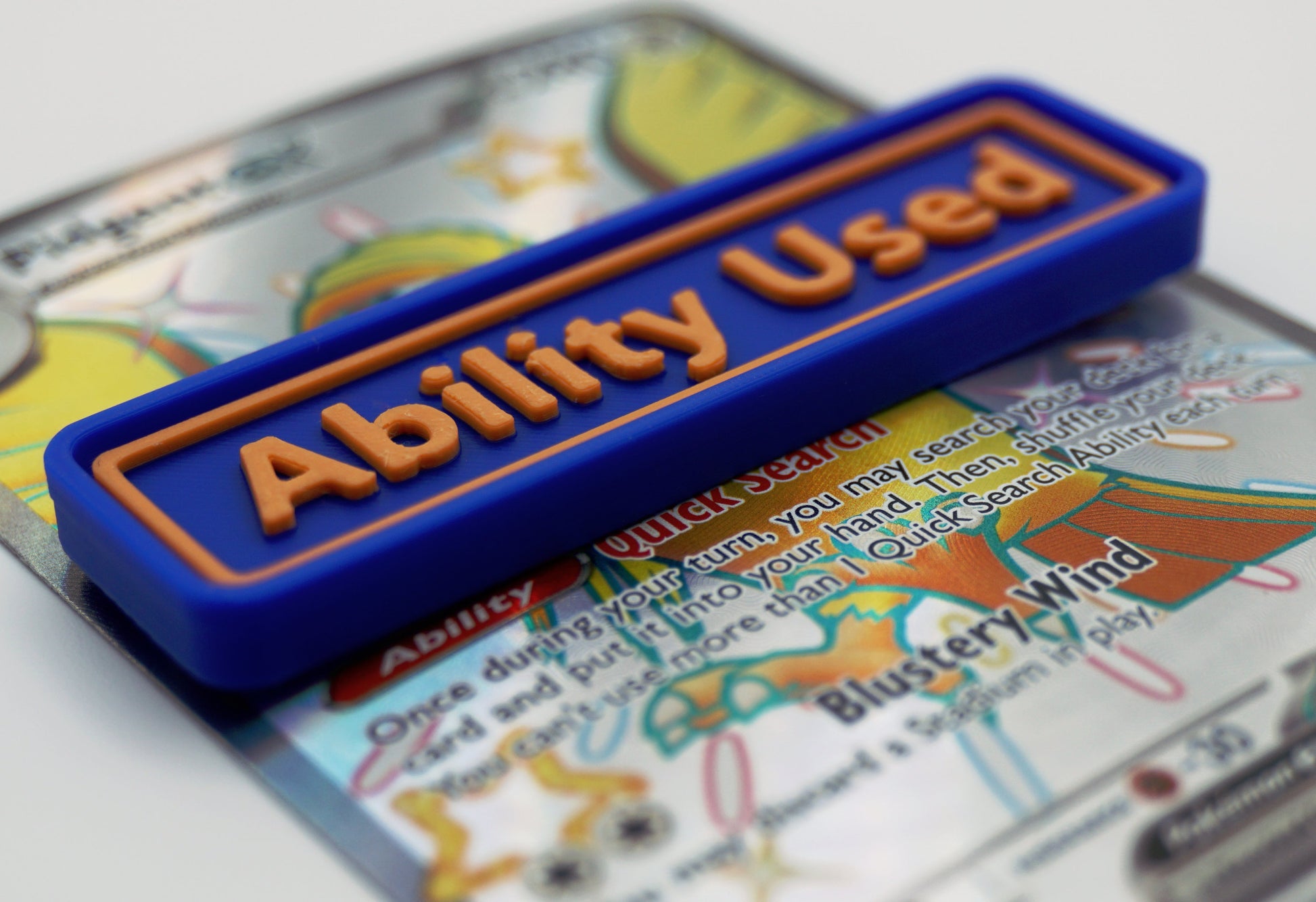 A blue Ability Used marker with orange text shown on top of a Shiny Pidgeot card from the Pokemon TCG.