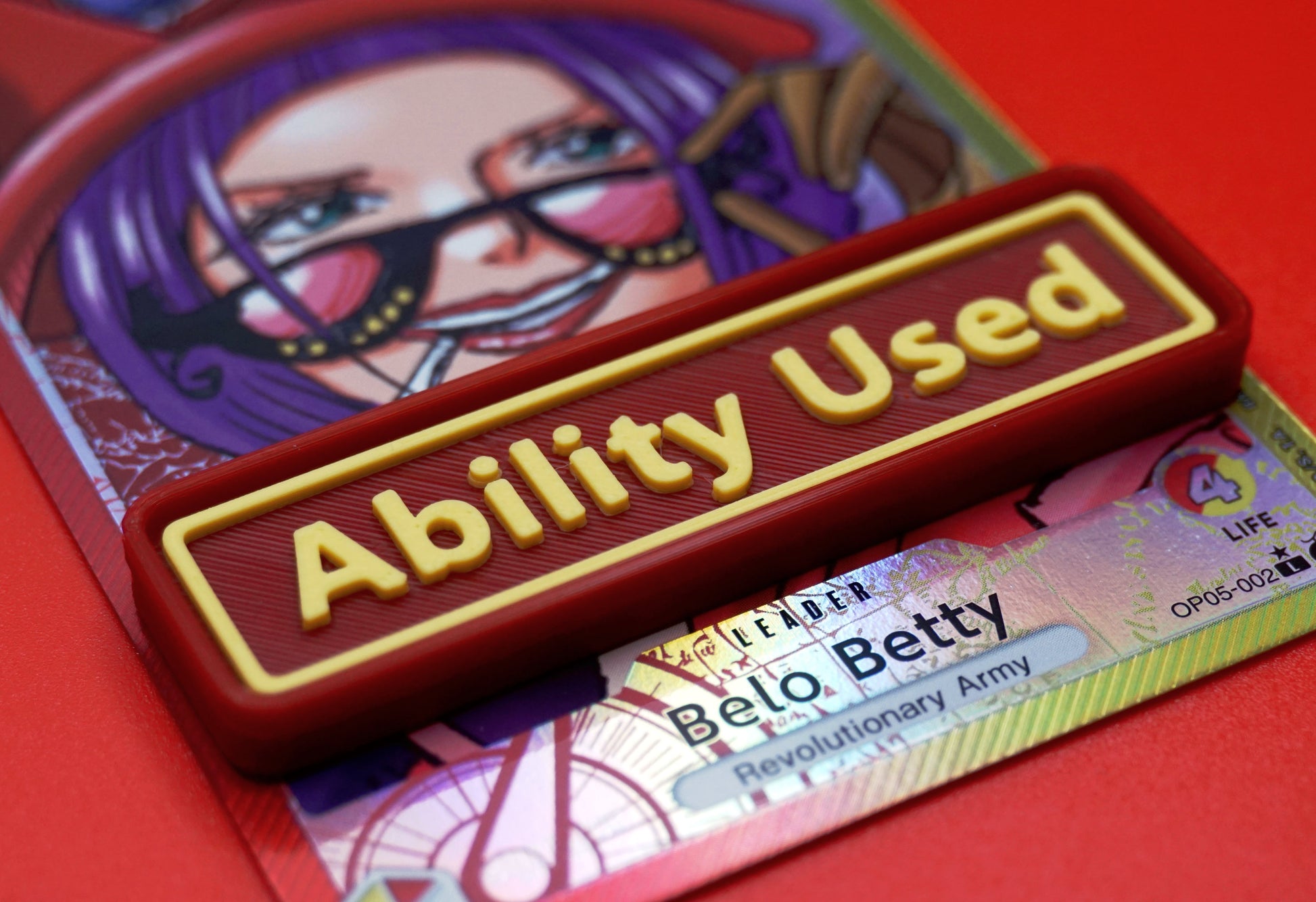 A red Ability Used marker with yellow text shown on top of a Belo Betty card from the One Piece TCG.