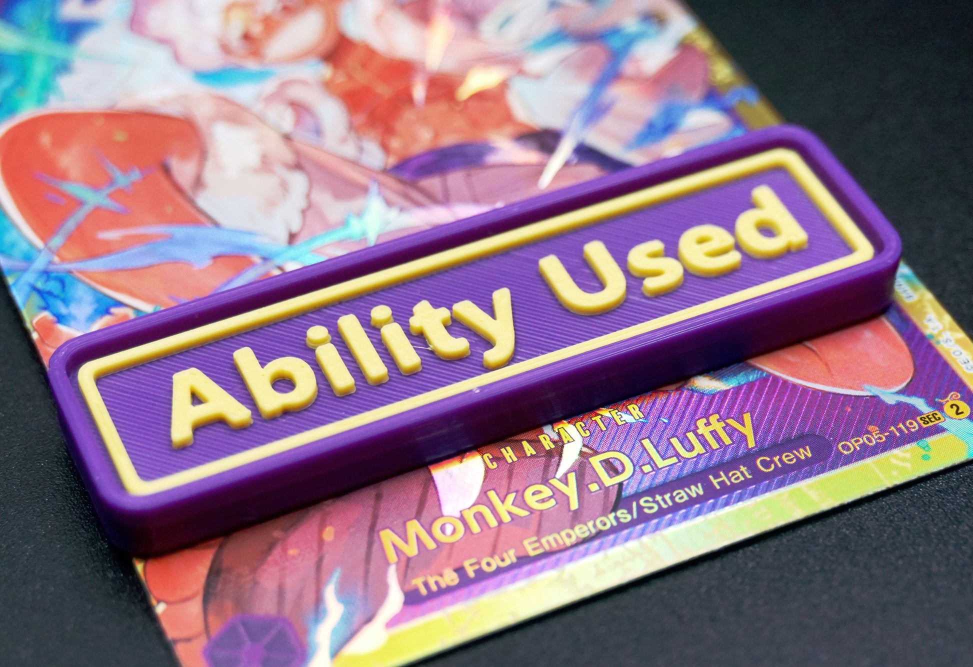 A purple Ability Used marker with yellow text shown on top of a Luffy card from the One Piece TCG.