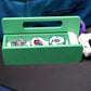 The Garage Door style deck box for Beyblade X in green for the base with a white door and tray. With Weiss Tiger, Meteor Dragoon, Dran Blast inside the case. Next to it is a Takara Tomy stadium in a case with a white launcher and purple rip cord with a slip grip attachment and handle