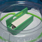 The Garage Door style deck box for Beyblade X in green for the base with a white door and tray. With Weiss Tiger, Meteor Dragoon, Dran Blast inside the case. With the deck box sitting inside a Takara Tomy stadium with Level Locks from Momo's Models