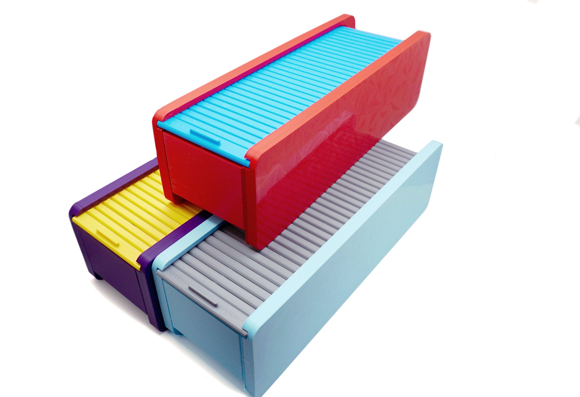 The Beyblade X Garage Door style deckbox from Momo's Models shown in purple and yellow color scheme, red and sky blue color scheme, and the glacier with grey color scheme. With everything against a white background