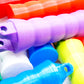 A pile of the Beyblade X Full Grip Handles, colors shown in the pile are green, purple, white, blue, sky blue, lime, red, and orange