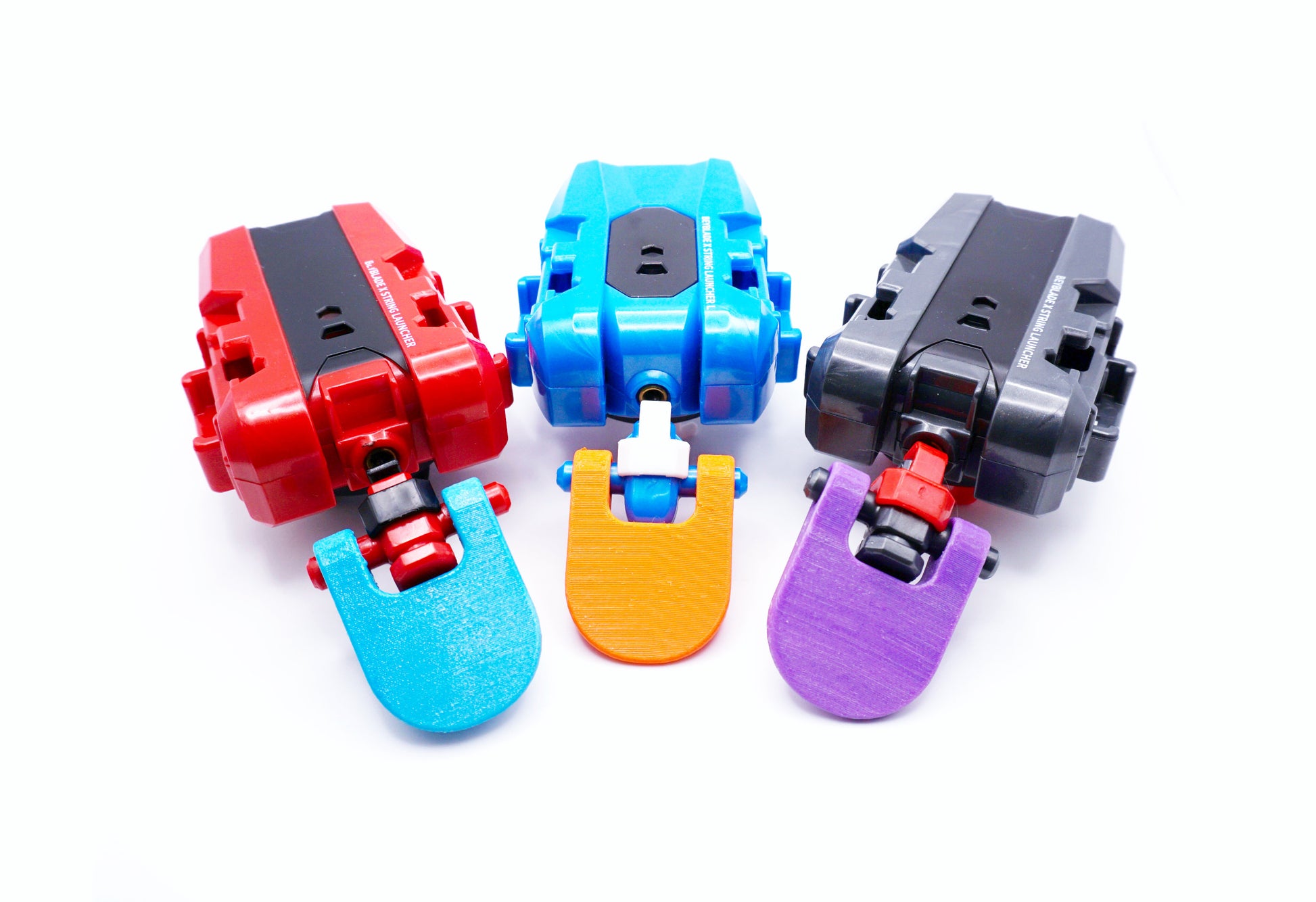 The Beyblade X Launcher Tab displayed in 3 colors, sky blue, orange, and purple, on different colored string launchers against a white background