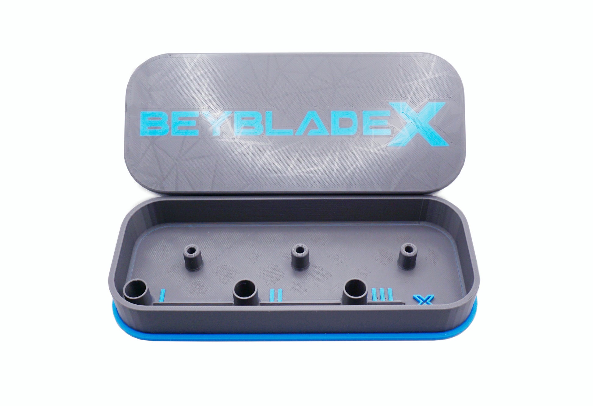 A gray rectangular case with a blue trim and the text "BEYBLADE X" in sky blue. The case is open, revealing several cylindrical holders inside. The lid has a geometric pattern.