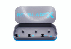 A gray rectangular case with a blue trim and the text "BEYBLADE X" in sky blue. The case is open, revealing several cylindrical holders inside. The lid has a geometric pattern.