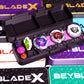 A variety of the Slam Shell EX deck boxes with one fully open showing off 3 beyblades inside it, Shark Scale, Aero Pegasus, and Delta Unicorn, with a 7-60 ratchet, and multiple its