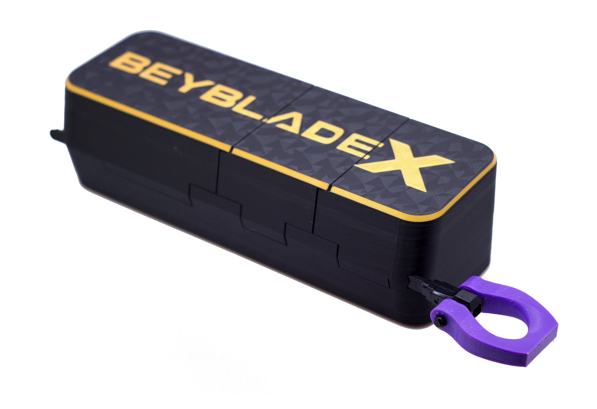 A Beyblade X Slam Shell EX storage case in black with a diamond pattern, featuring gold lettering and a purple carrying loop, shown on a white background.