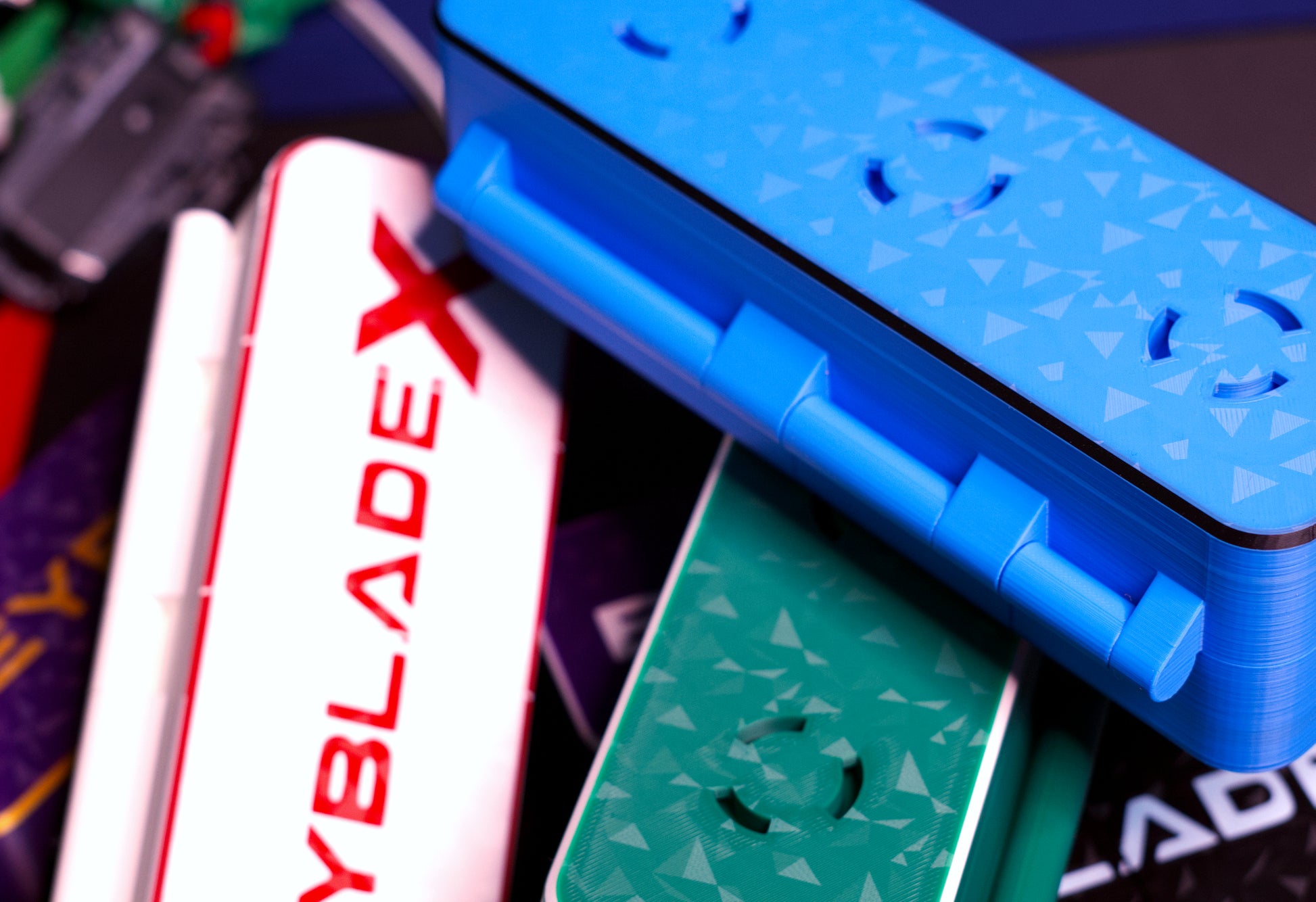 A variety of the Slam Shell EX deck boxes sitting on a table with a string launcher in the background. Showing the bottom of the Slam Shell EX deck box with the launcher holder.