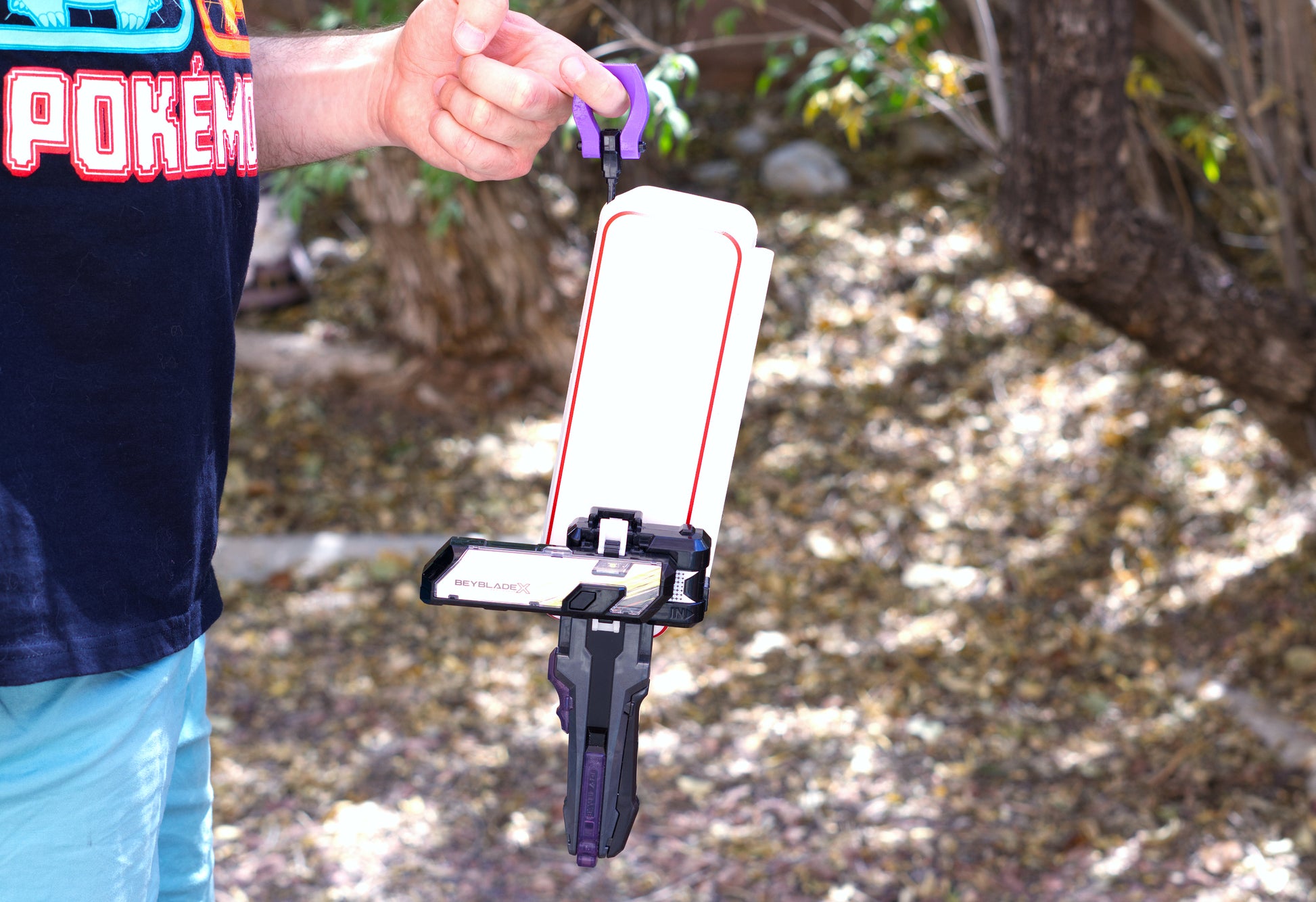 Holding the Slip Grip on a rip cord to hold the Slam Shell EX deck box shown in white with red trim, while a ripcord launcher is attached to the bottom of the deck box