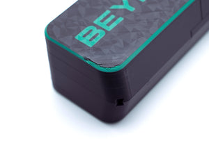 Close-up of a black rectangular electronic device with a textured top surface, featuring the partial brand name 'BEY' in bright green and a thin green accent line along the edge, set against a plain white background.