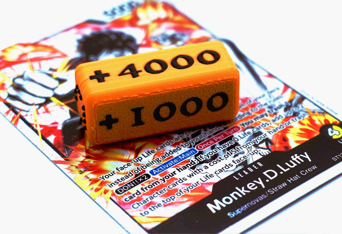 Attack Increase marker in orange and black on top of a Monkey D Luffy alt art leader card for One Piece TCG