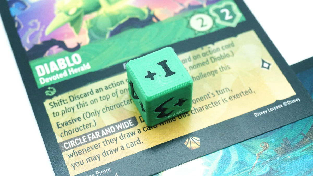 Mini Positive Dice shown in green and black on top of a Diablo card from the Lorcana TCG