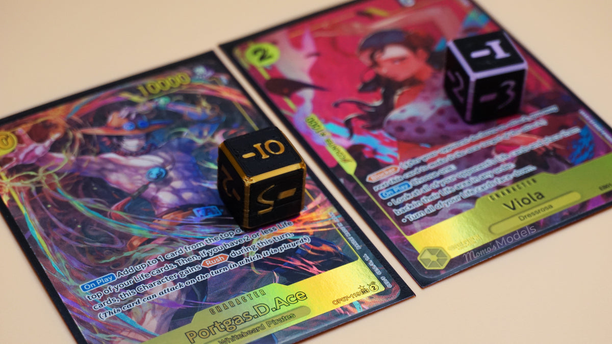 Negative Dice shown in black gold and black lavender, on top of 2 different One Piece TCG OPTCG cards