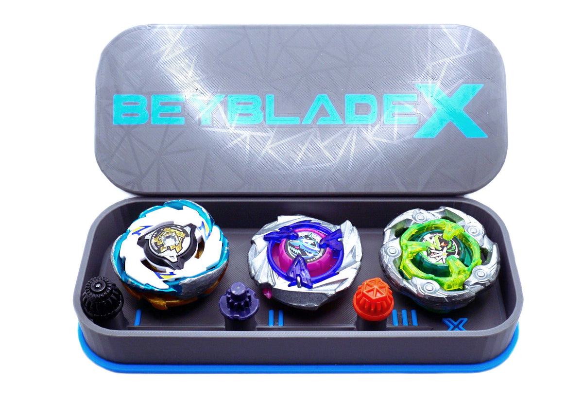 The Beyblade X Pocket deck box in grey and sky blue. Currently open revealing the three beys inside which include Emperor Pegasus Blast Heavy 3-60 Level, Shark Scale 1-70 Low Rush, and Wizard Rod (Wand Wizard) 1-60 Hexa