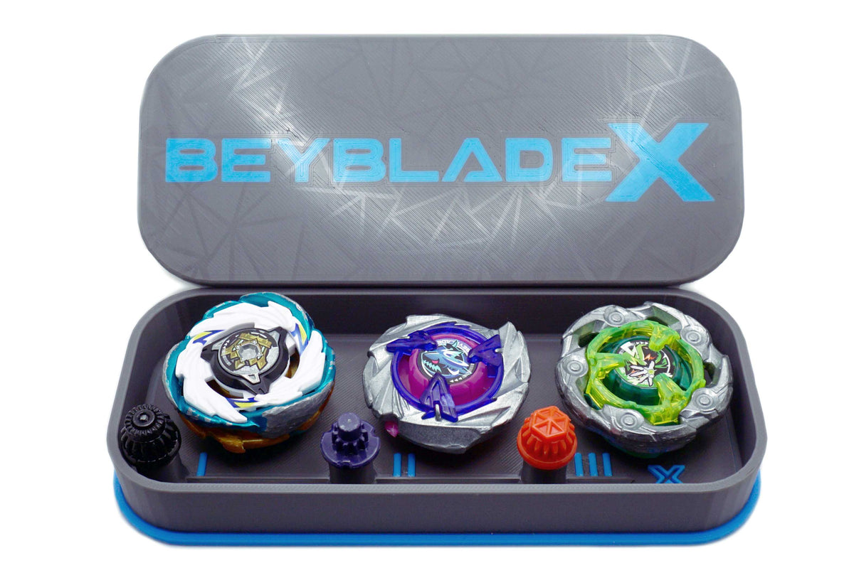 The Beyblade X Pocket deck box in grey and sky blue. Currently open revealing the three beys inside which include Emperor Pegasus Blast Heavy 3-60 Level, Shark Scale 1-70 Low Rush, and Wizard Rod (Wand Wizard) 1-60 Hexa