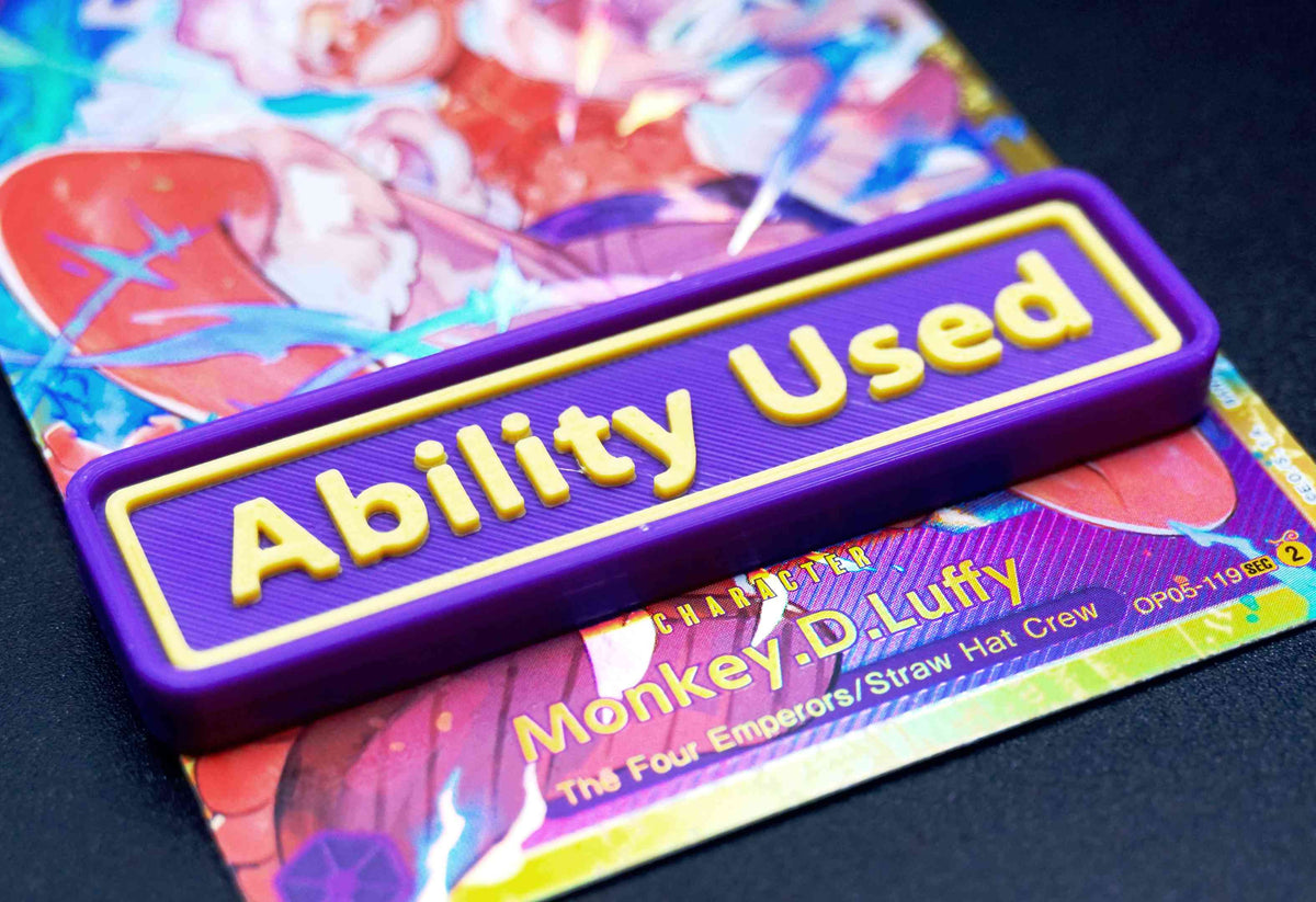 A purple Ability Used marker with yellow text shown on top of a Luffy card from the One Piece TCG.