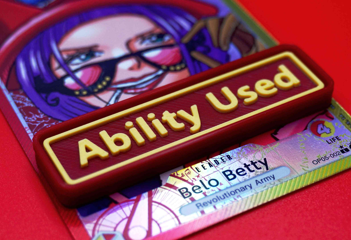 A red Ability Used marker with yellow text shown on top of a Belo Betty card from the One Piece TCG.